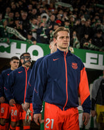 Person wearing a sports team jacket with visible branding in a stadium setting