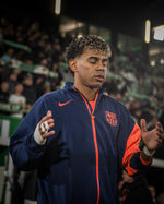 Person wearing a sports jacket with a logo in an indoor setting