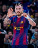 Person wearing a Barcelona soccer jersey with visible tattoos and a beard, in front of a blurred crowd.