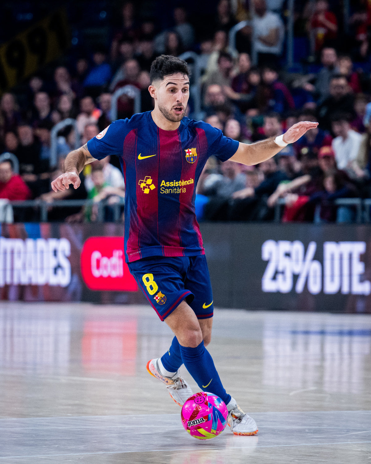 Soccer player in a match wearing a Barcelona jersey with a colorful ball.
