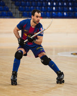 Man playing roller hockey in a sports arena with blue seats.