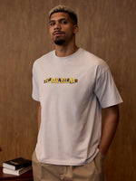 Man wearing a gray t-shirt with 'FC Barcelona' printed on it against a wooden background.