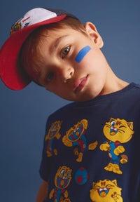Child wearing a navy blue t-shirt with cartoon characters against a blue background