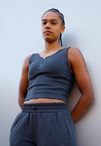 Person wearing a dark gray tank top and matching pants against a light background
