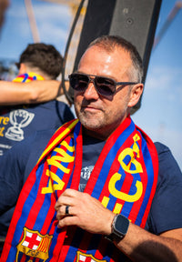 Man wearing sunglasses and a Barcelona scarf with a blue background