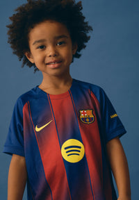 Child wearing a sports jersey with a prominent logo on a blue background