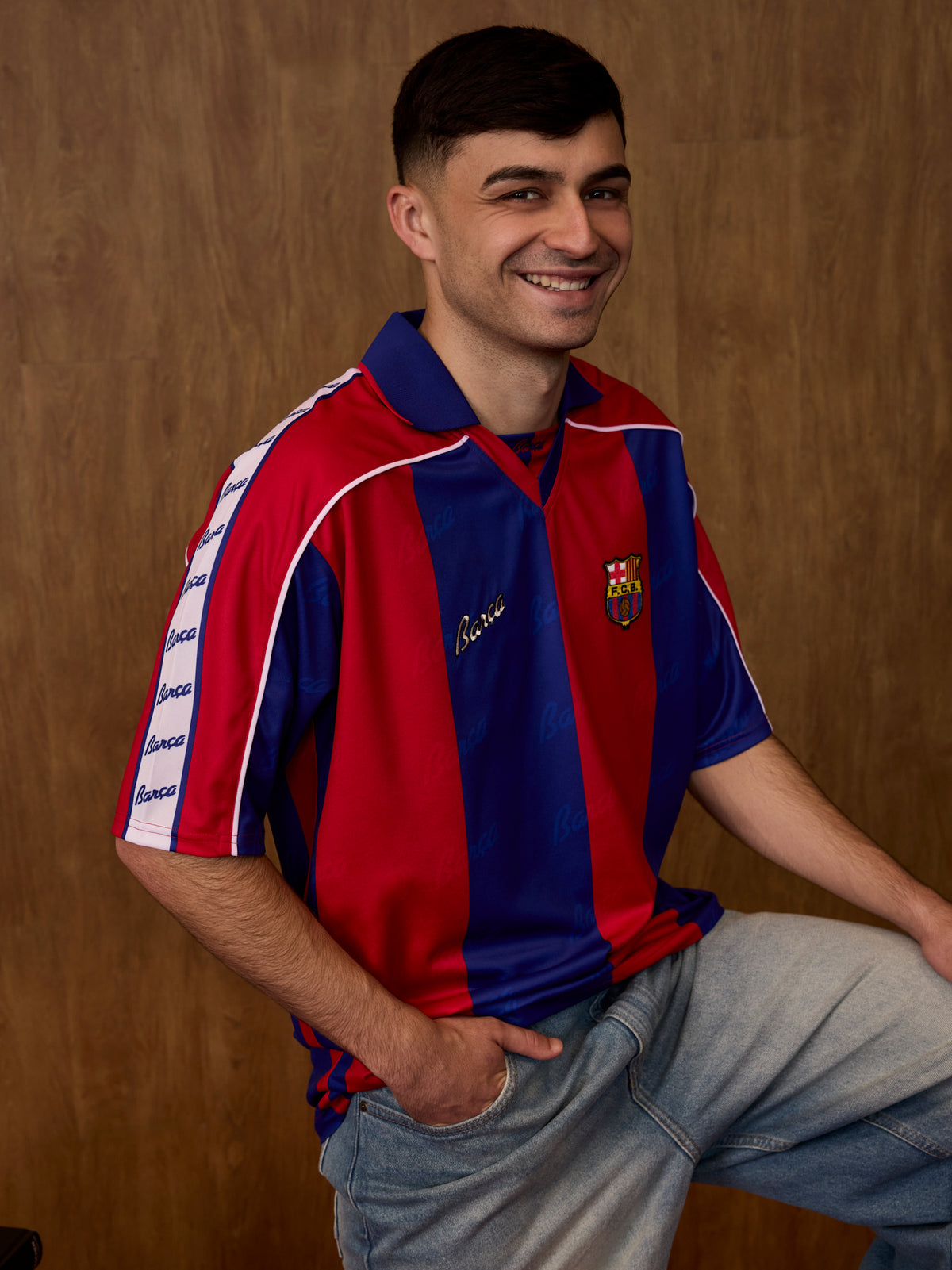 Vista frontal d’una samarreta del FC Barcelona posada per un model, amb franges verticals vermelles i blaves, coll marí i l’escut del club al pit.