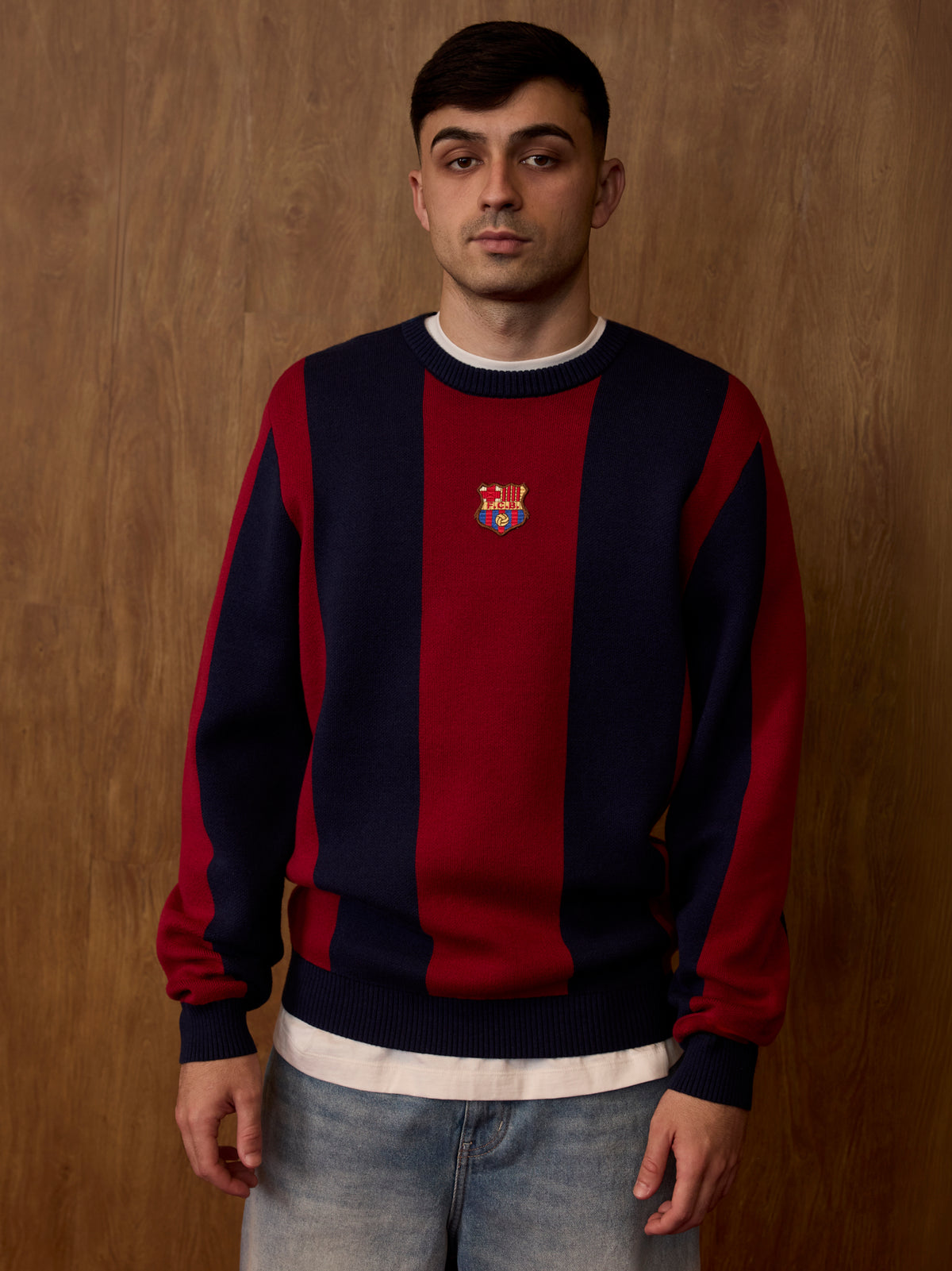 Front view of a FC Barcelona sweater worn by a model, with wide navy and garnet vertical stripes and the club crest centered on the chest.