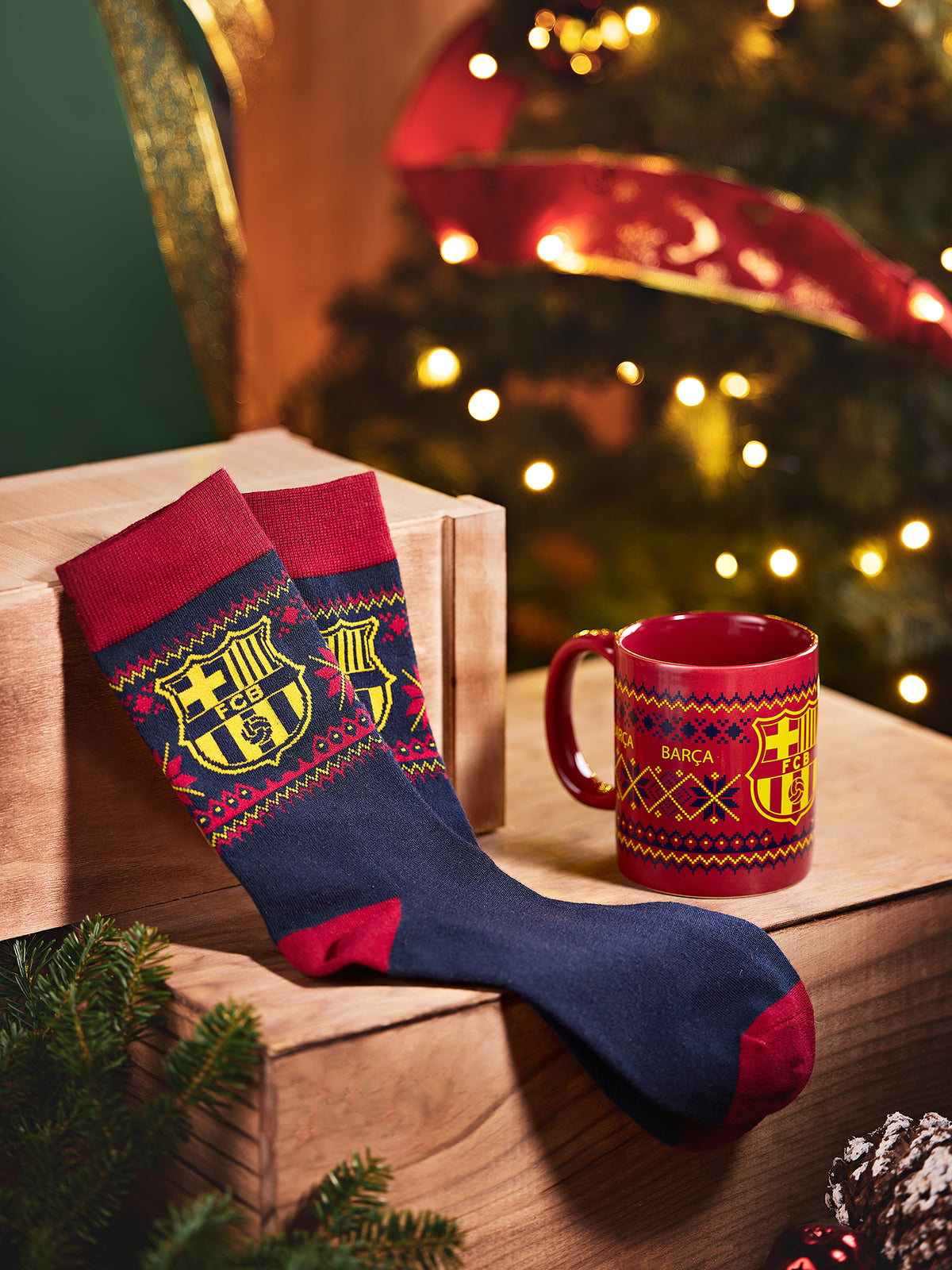 Calcetines de FC Barcelona en azul marino y rojo con un escudo grande, junto a una taza de Barça a juego en un ambiente festivo navideño.