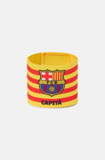 Yellow and red striped FC Barcelona captain's armband featuring the club crest and the word "CAPITÀ" printed in black.