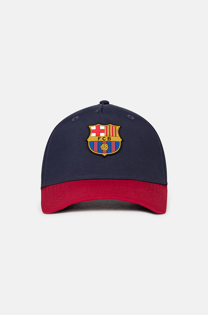 Two-tone FC Barcelona baseball cap featuring a navy blue crown and a red brim, with the club’s full-color crest embroidered on the front.