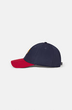 Two-tone FC Barcelona baseball cap featuring a navy blue crown and a red brim, with the club’s full-color crest embroidered on the front.