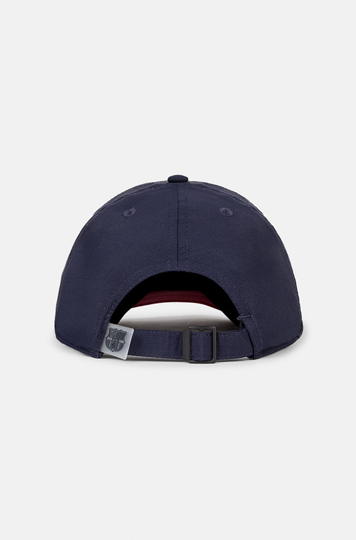 Two-tone FC Barcelona baseball cap featuring a navy blue crown and a red brim, with the club’s full-color crest embroidered on the front.