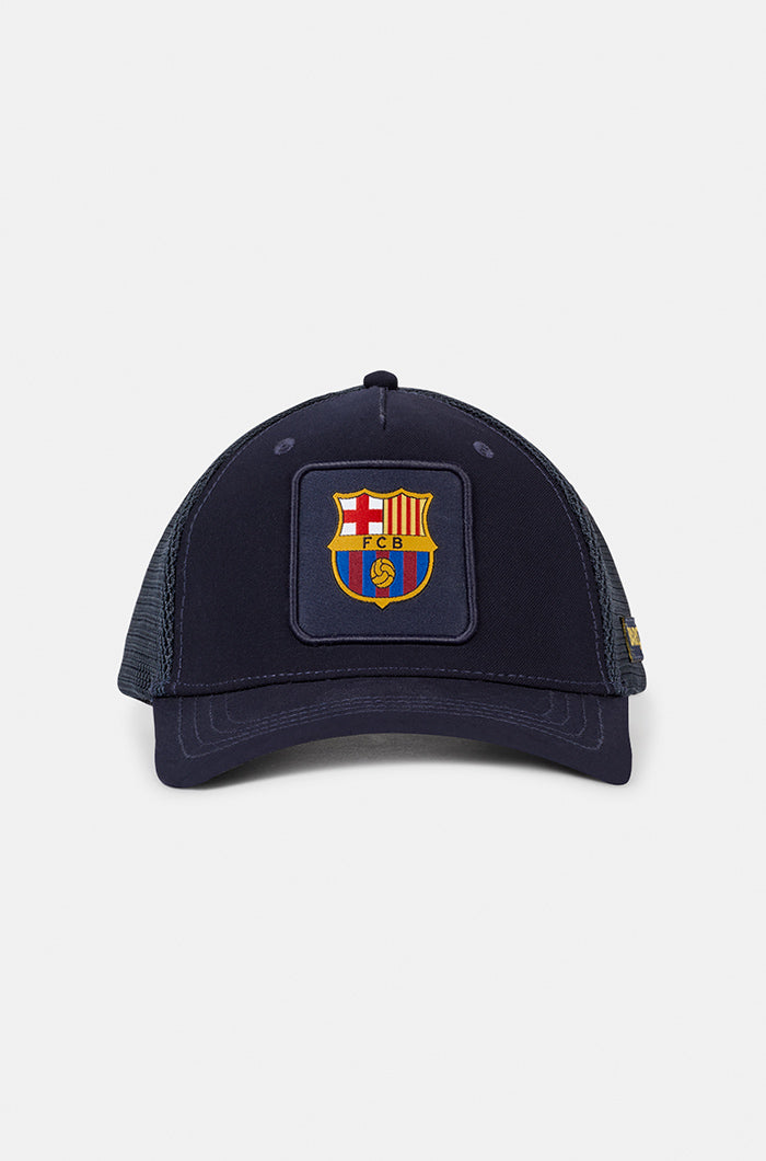 Navy blue FC Barcelona trucker cap with mesh back, embroidered club crest patch on the front panel, and the word “BARÇA” in yellow on the side.



