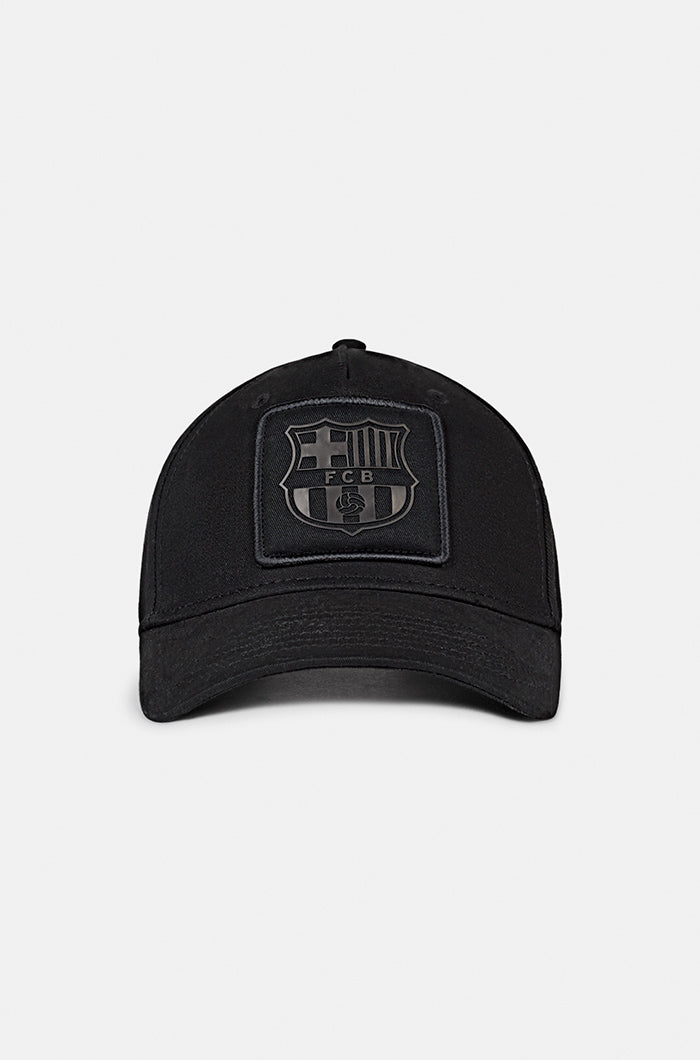 Black FC Barcelona baseball cap with a matte black crest patch on the front and the word "BARÇA" embroidered on the side, featuring a curved brim and structured fit.