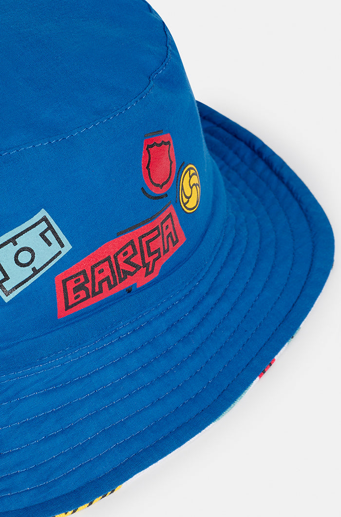 Blue FC Barcelona bucket hat with minimal embroidered graphics on the front, including a red crest, yellow football, and the word "Barça" in red.