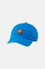 Bright blue FC Barcelona baseball cap featuring the club’s full-color crest on the front and a red Nike swoosh embroidered on the side.