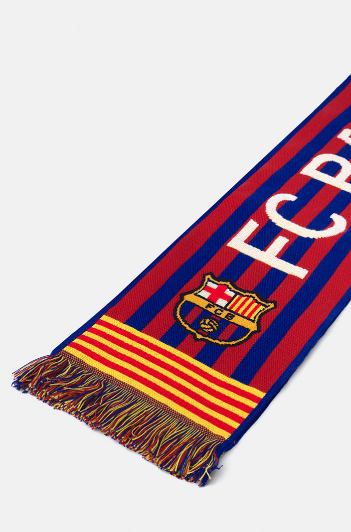Double-sided FC Barcelona scarf in red, yellow, and blue stripes, featuring the club crest and bold white text reading 'FC BARCELONA