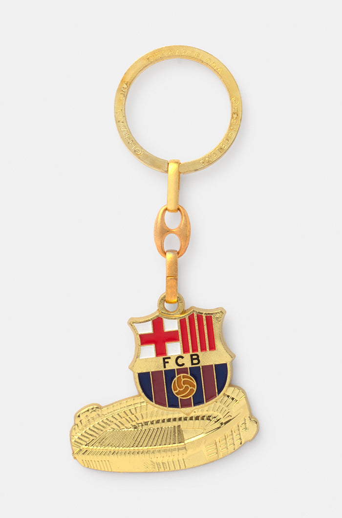 Gold-colored keychain featuring the FC Barcelona crest above a miniature engraving of the Camp Nou stadium.