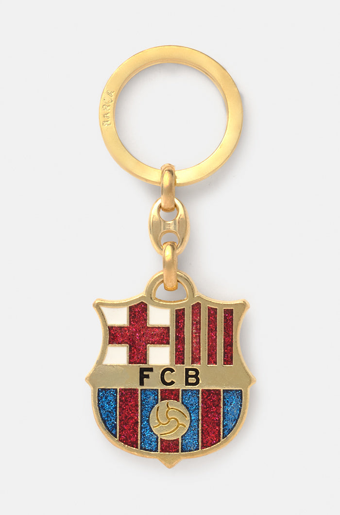 Gold-colored keychain featuring the FC Barcelona crest with glittery red and blue enamel accents.










